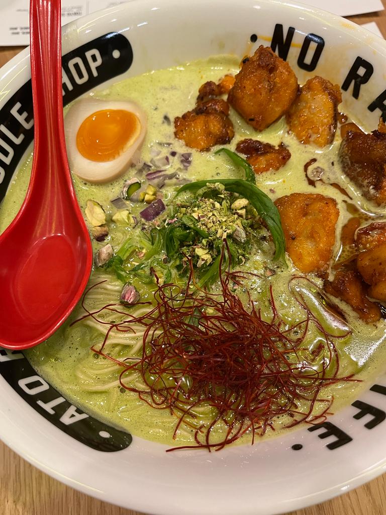 RAMEN PISTACJOWY z Ato Ramen w głębokim talerzu z czerwoną łyżką.