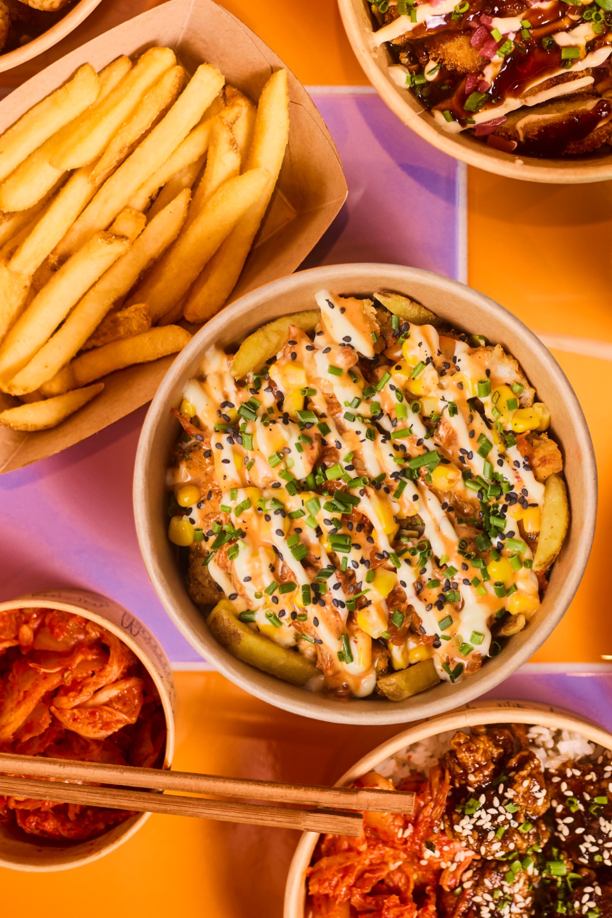 K-fryty Smakosza, czyli micha w rozmiarze L z frytkami i smażonym kurczakiem w posypce serowej (oba produkty obtoczone), smażonym kimchi, sałatą lodową, kukurydzą i limitowanym sosem gochujang z miodem — stworzonym specjalnie pod to danie — przyozdobiona szczypiorkiem, czarnym sezamem i sosem mayo — Solleim