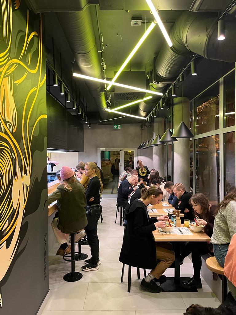 Wnętrze restauracji ATO RAMEN. Sala ze stolikami. Jedzący ludzie.